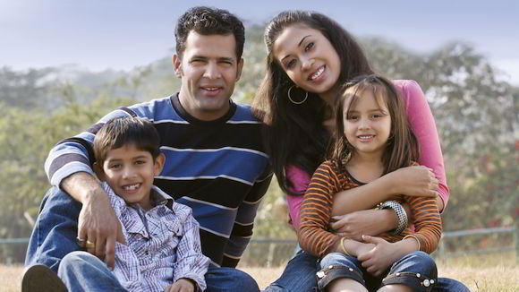 Smiling parents with two children sitting on ground